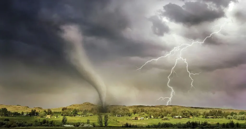 A tornado touches down on a green field with lightning and dark clouds in the sky.